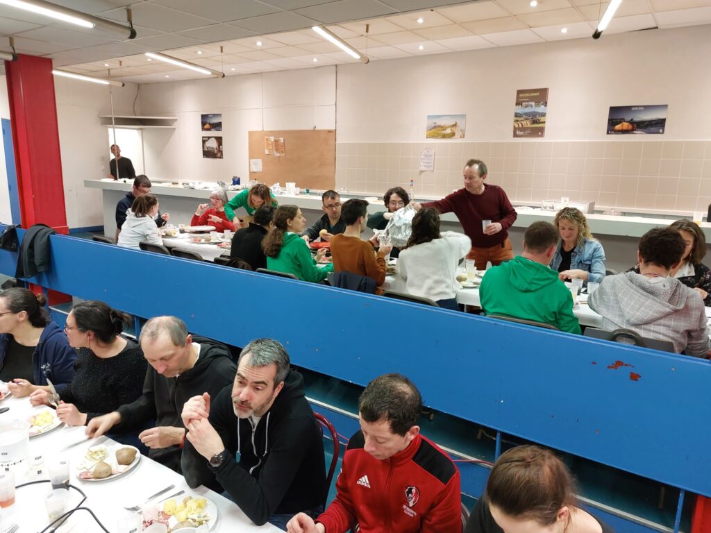 Le repas du samedi soir : deux longues tablées de convives, plusieurs portant le sweat vert du club.