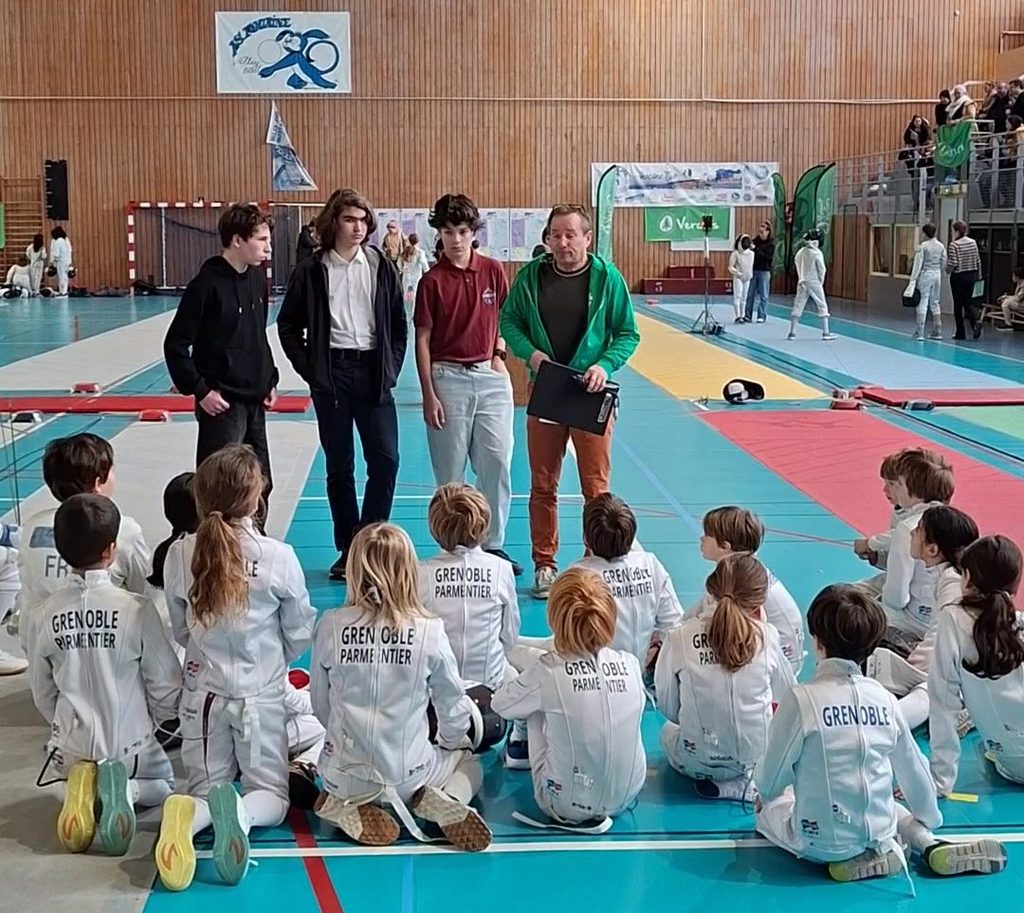 Le briefing d’avant-compétition au tournoi Bayard 2026 : les jeunes escrimeurs assis sur la piste, face aux organisateurs