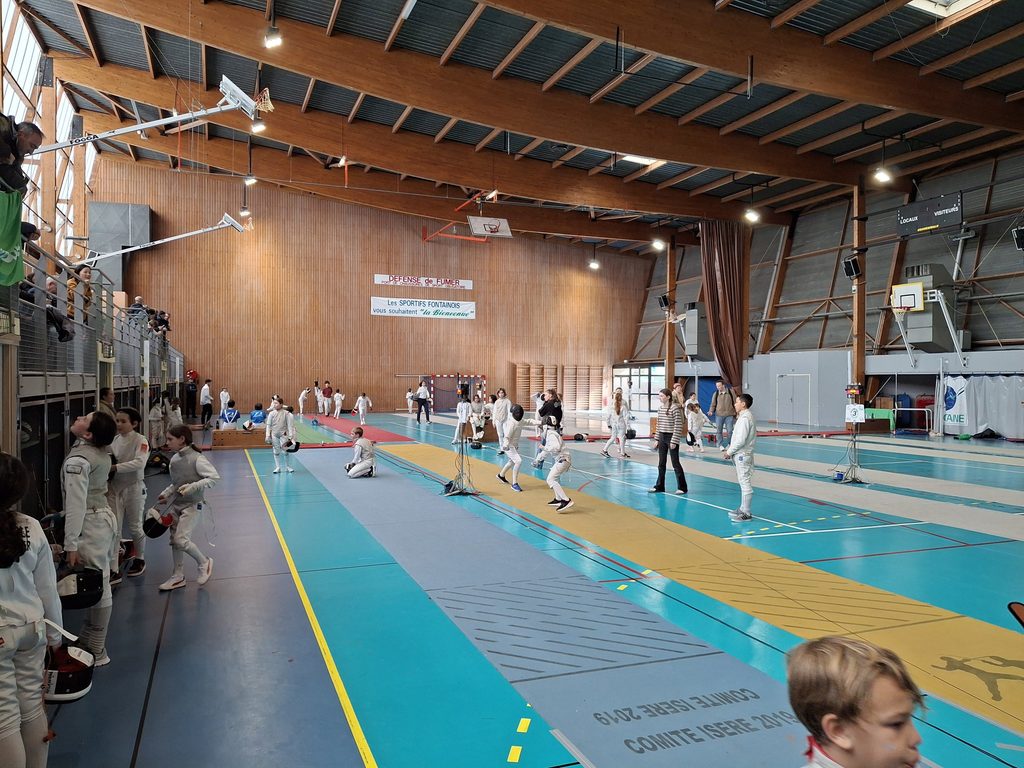 Le tournoi Bayard 2026 au gymnase Jules Vallès de Fontaine : de jeunes escrimeurs sur les pistes et des parents dans les gradins.