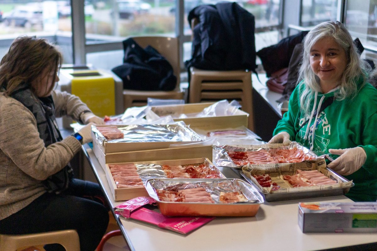 Deux bénévoles gantées disposent la charcuterie sur des plateaux